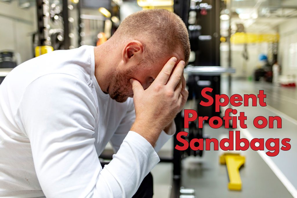A gym owner holds his head in his hands near the text "spent profit on sandbags."