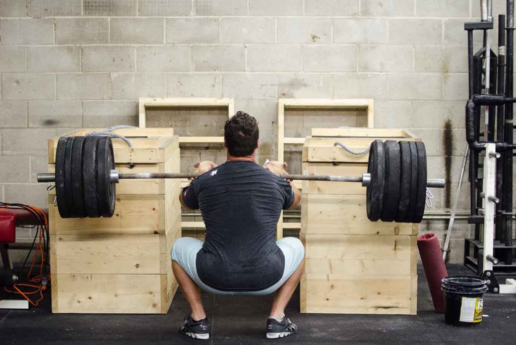 An athlete performs a heavy barbell front squat in a gym.