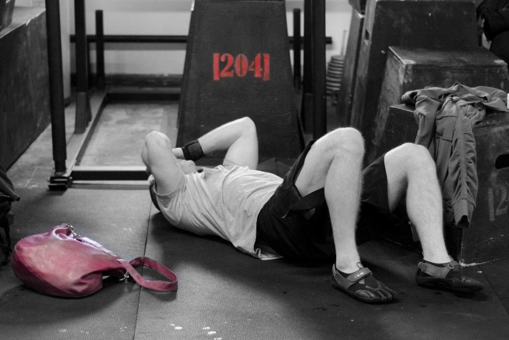 A client writhes on the floor after a tough workout at a CrossFit gym.