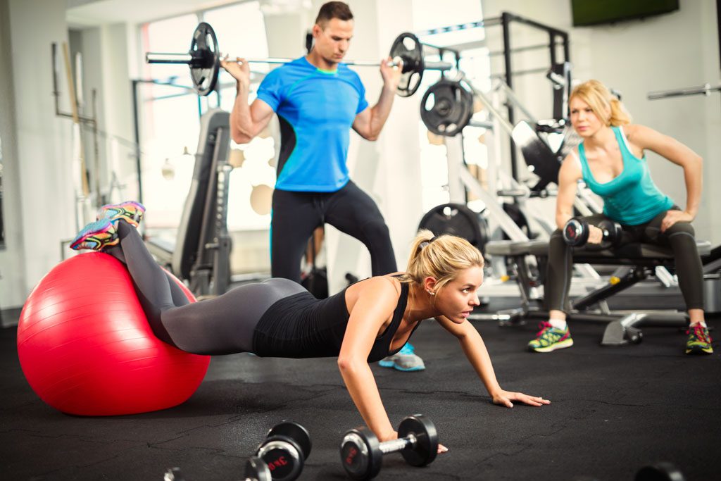 A group of clients does a workout in a gym as part of a small-group training program.