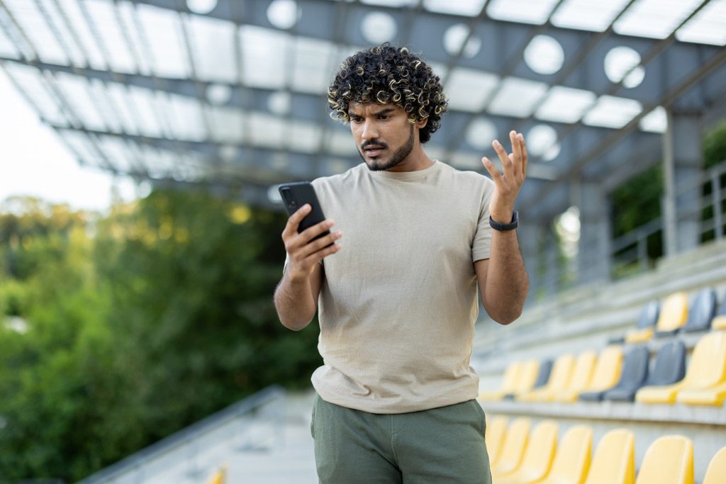 A confused man looks at his cell phone in the middle of an AI-programmed workout.