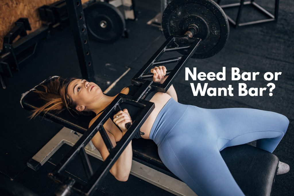 A woman performs bench presses with a football or Swiss bar.