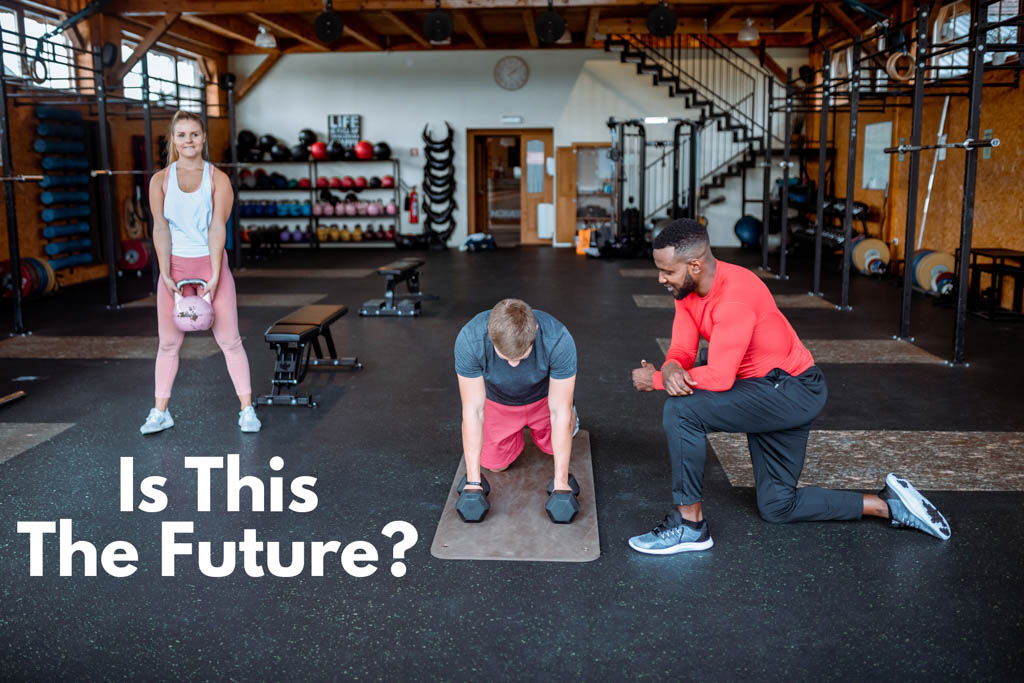 A fitness coach serves two clients at once in a small-group personal training gym.