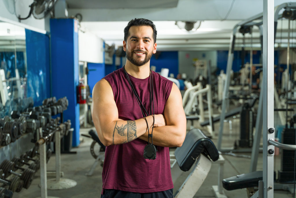 A smiling, confident gym owner stands in his training area.