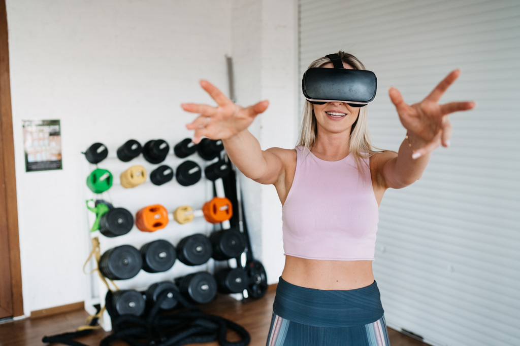 A woman uses a VR headset in a gym.