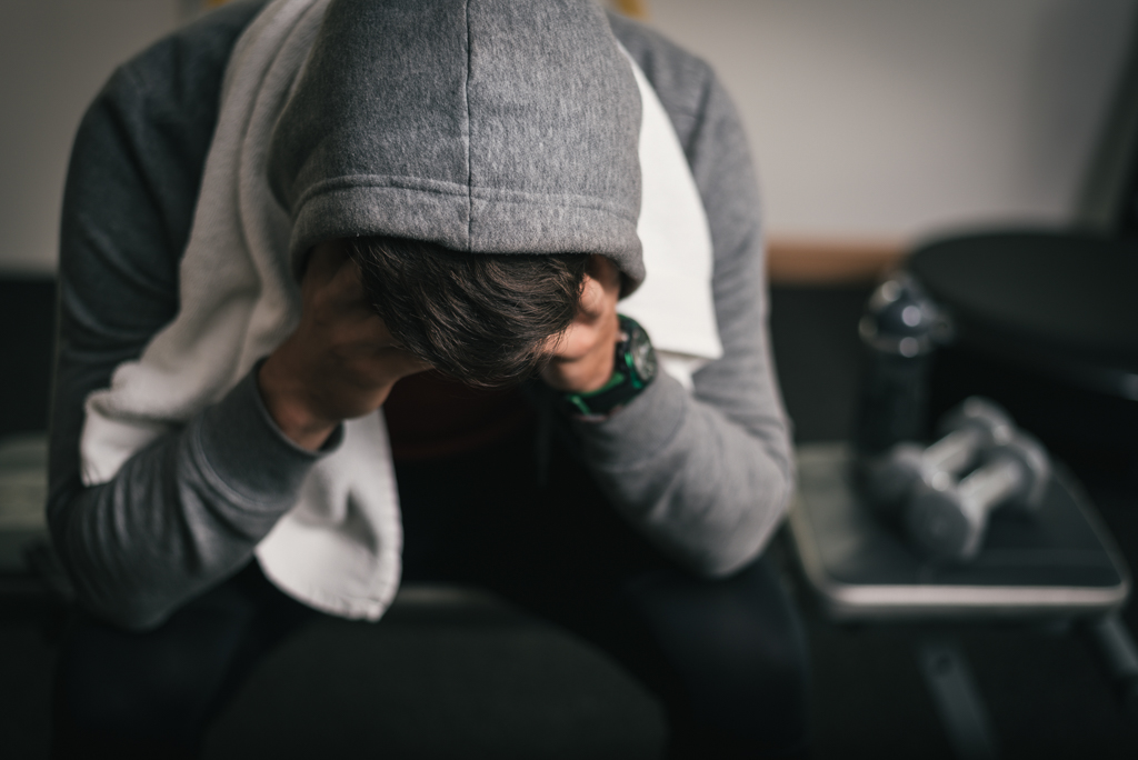 An exhausted gym owner holds his head in his hands.