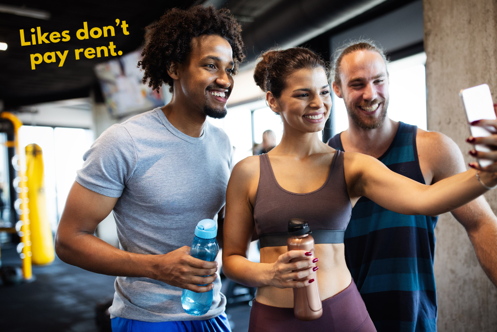 Text "Likes don't pay rent." over photo of gym members taking a selfie